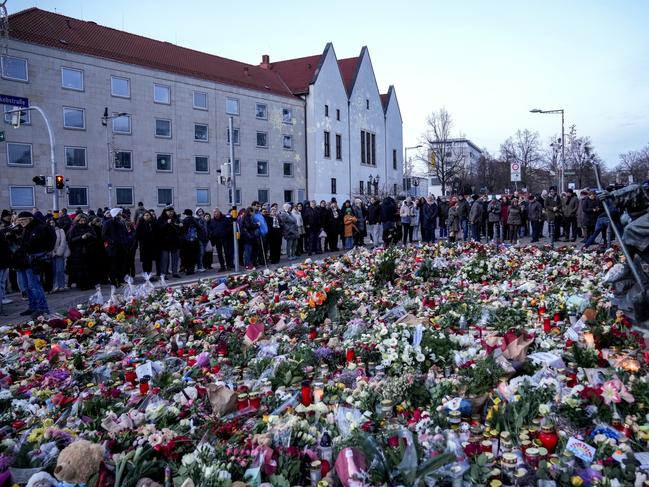 People lay flowers and lit candles in front of the Johannis church close to the Christmas market, where a car drove into a crowd on Friday evening, in Magdeburg, Germany, Sunday, Dec. 22, 2024. (AP Photo/Ebrahim Noroozi)