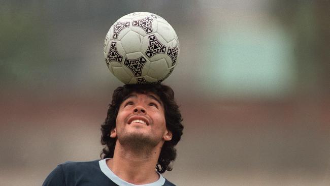 Argentine football star Diego Maradona, wearing a diamond earring, balances a soccer ball on his head as he walks off the practice field following the national selection's practice session in Mexico City in 1986.