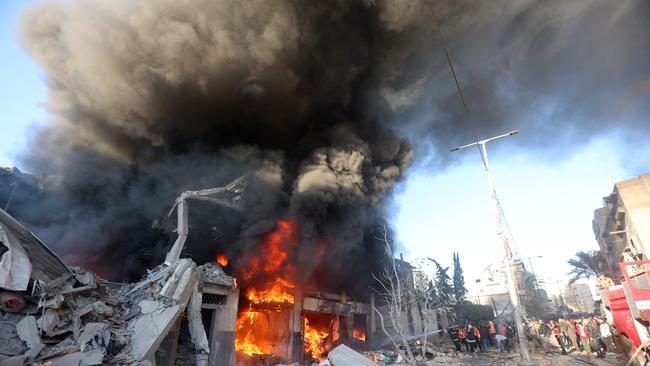 People watch as firefights battle flames in a building hit by an Israeli strike in Khan Yunis. Picture: AFP