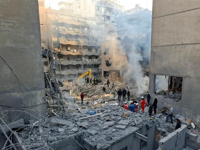 People gather as rescuers sift through the rubble of a levelled building, following an overnight Israeli air strike that targeted Beirut’s Basta neighbourhood on Saturday. Picture: AFP