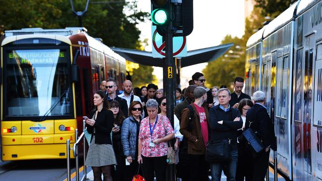 Morning peak hour tram commuters arrive at Pirie Street tram stop on King William Street. Image AAP/Mark Brake.