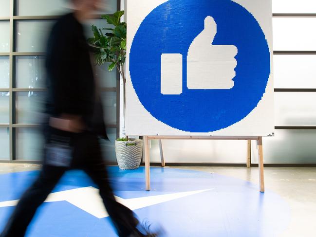 A Facebook employee walks by a sign displaying the 