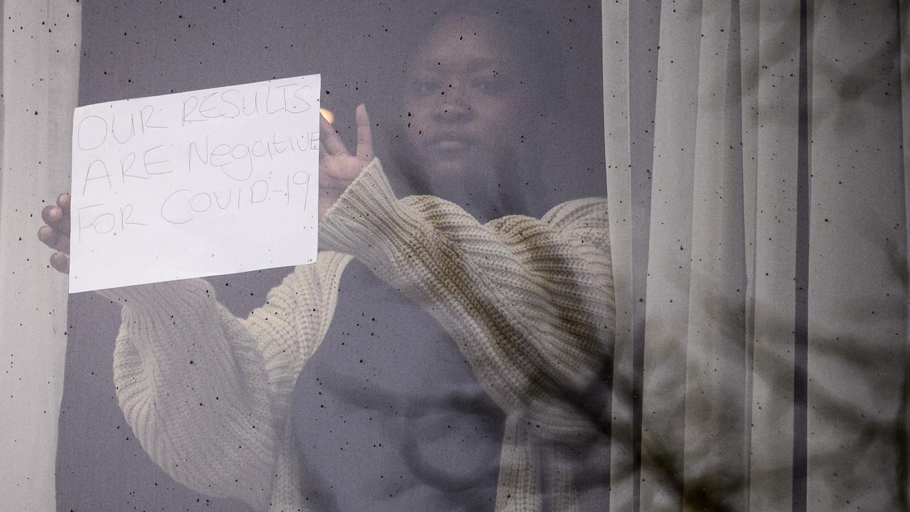 A woman holds up a sign reading ‘Our results are negative for COVID-19’ from her room at the Radisson Blu hotel close to London’s Heathrow Airport. Picture: Leon Neal/Getty Images.