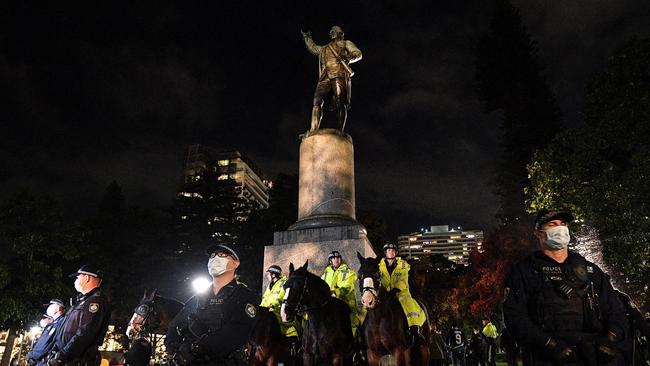 Police stand guard at the statue of Captain Cook in Sydney’s Hyde Park during a protest rally against Aboriginal deaths in custody on Friday night.