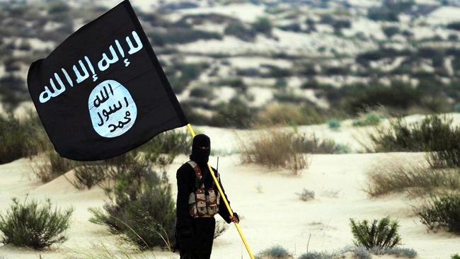 A masked Islamic State soldier poses holding a banner. Picture: Getty Images.