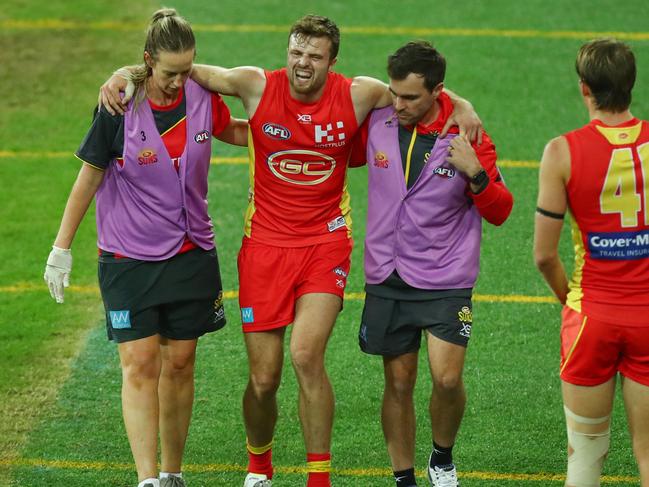 Gold Coast’s Jordan Murdoch limps off the ground with a suspected ankle injury. Picture: Getty Images