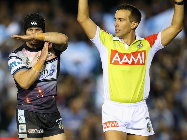 Michael Ennis of the Sharks gestures as the referee refers a try.