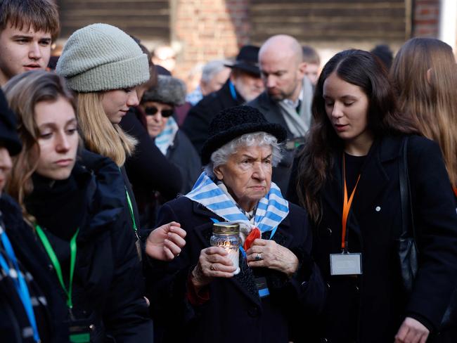 Survivors, relatives and representatives of the Memorial and Museum Auschwitz-Birkenau lay wreaths and light candles at the so-called Death Wall next to the former Block 11 of the former Auschwitz I main camp in Oswiecim, Poland on January 27, 2025, during commemorations on the 80th anniversary of the liberation of the German Nazi concentration and extermination camp Auschwitz-Birkenau by the Red Army. (Photo by Wojtek RADWANSKI / AFP)