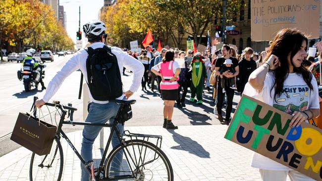 A man on a bike watches protesters marching down King William Road for the Adelaide School Strike 4 Climate Protest. Picture: NCA NewsWire / Morgan Sette