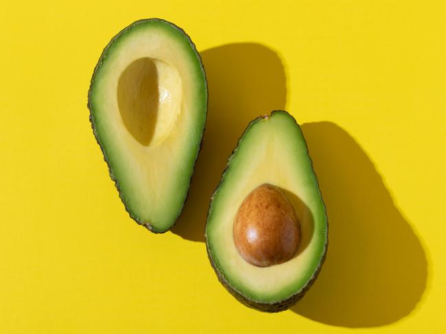 EMBARGO FOR TWAM 17 SEPTEMBER 2022. FEE MAY APPLY.  Avocado halves close up with trendy hard shadow and hard light on yellow background, minimalist