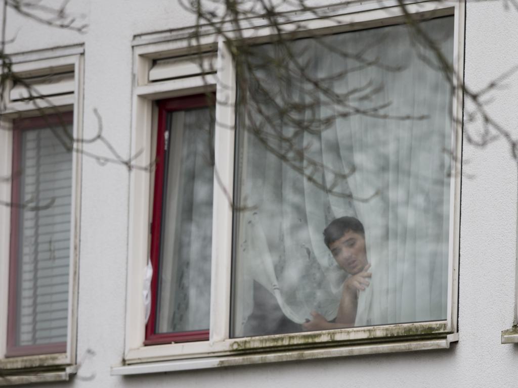 A resident peers from a window as Dutch counter terrorism police prepare to enter a house after a shooting in Utrecht, Netherlands. Picture: AP