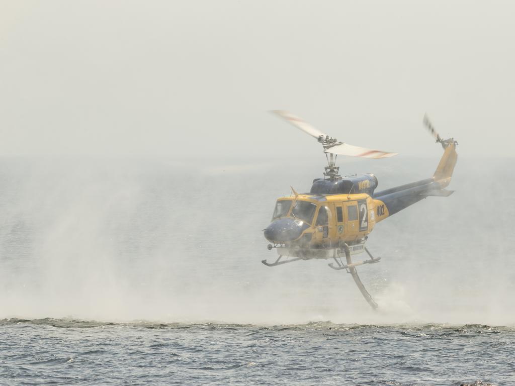 A water-bombing helicopter fills up at Great Lake. Picture: Heath Holden/Getty