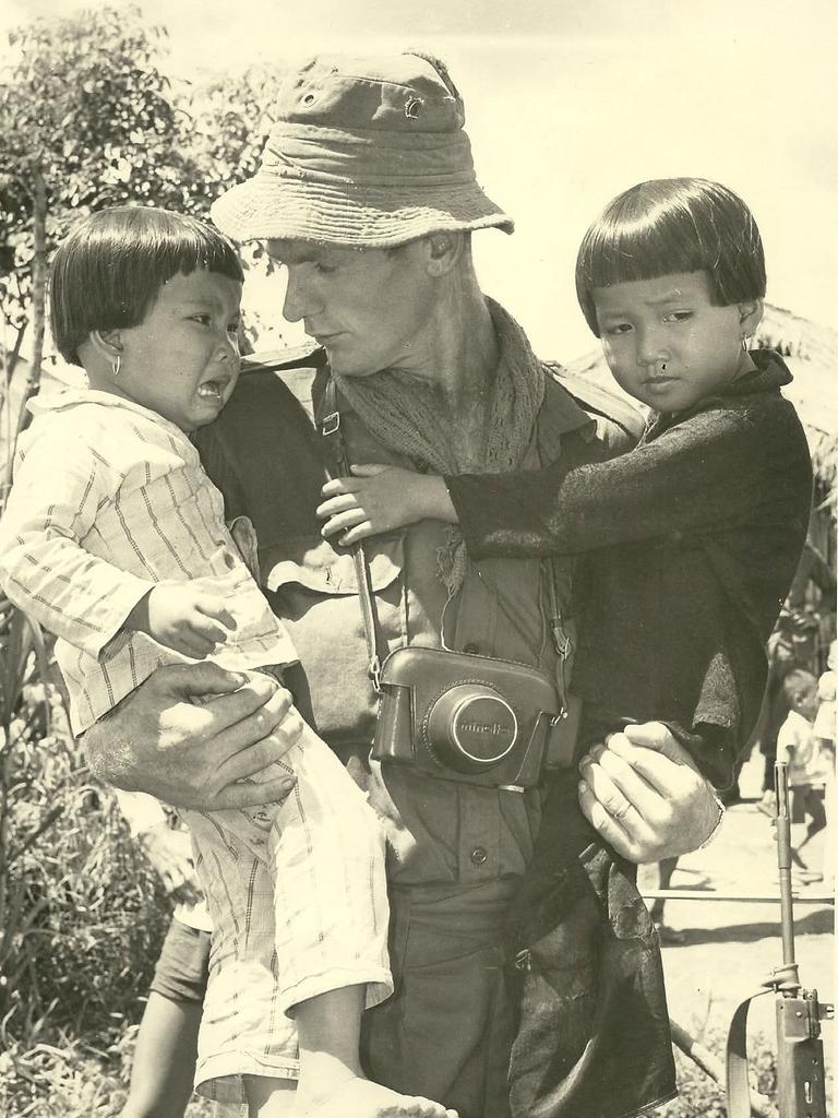 Harry Dennis holds two local children in his arms during a visit to Ong Huhn Village during the Vietnam War. Picture: Supplied