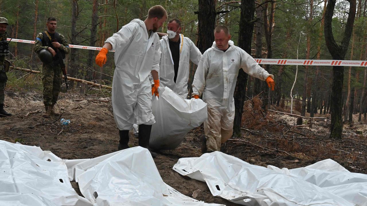 Forensic technicians carry a body bag in a forest on the outskirts of Izyum. Picture: Sergey Bobok/ AFP.