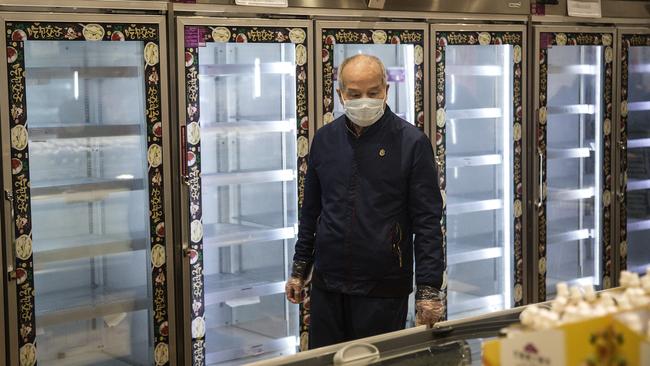 A man wears a protective mask as he passes by empty shelves in a Wuhan supermarket. Picture: Getty Images