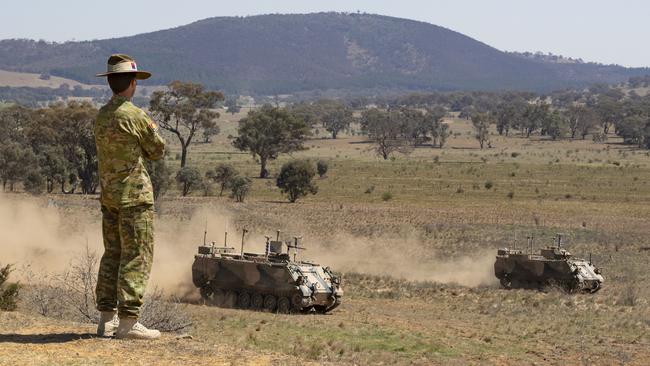 An Australian Army officer watches two fully autonomous M113 AS4 optionally crewed combat vehicle (OCCV) in an experiential program run by BAE Systems Australia and TAS DCRC.