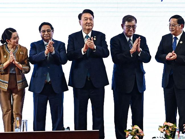 (L-R) Thailand's Prime Minister Paetongtarn Shinawatra, Vietnam's Prime Minister Pham Minh Chinh, South Korea's President Yoon Suk Yeol, Japan's Prime Minister Shigeru Ishiba, Laos' Prime Minister Sonexay Siphandone, and China's Premier Li Qiang clap on stage during a group photo at 27th ASEAN Plus Three Summit during the 44th and 45th Association of Southeast Asian Nations (ASEAN) Summits in Vientiane on October 10, 2024. (Photo by NHAC NGUYEN / AFP)