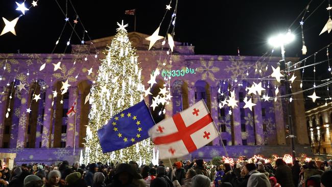 Protesters carry the flags of Georgia and the European Union outside the parliament after former soccer player Mikheil Kavelashvili was formally inaugurated as president of Georgia, in Tbilisi on Sunday. Picture: Giorgi Arjevanidze / AFP