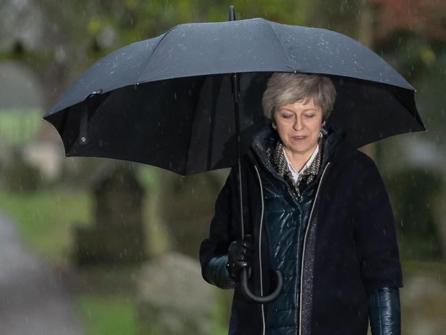 Britain's Prime Minister Theresa May shelters from the rain under an umbrella after attending a church service near to her Maidenhead constituency, west of London on December 9, 2018. - Theresa May wants to go down in history as the prime minister who safely steered Britain out of Europe -- a cause she did not believe in when the Brexit referendum was held. (Photo by Daniel LEAL-OLIVAS / AFP)