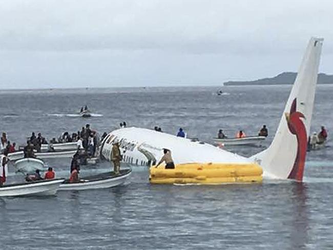 FILE - In this Sept. 28, 2018, file photo, local fishing boats move in to recover the passengers and crew of Air Niugini flight following the plane crashing into the sea on its approach to Chuuk International Airport in the Federated States of Micronesia. The airline operating a flight that crashed into a Pacific lagoon on Friday in Micronesia now says that one man is missing, after earlier saying that all 47 passengers and crew had safely evacuated the sinking plane. (James Yaingeluo via AP, File)