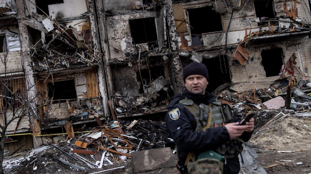 A Ukrainian police officer stands in front of a damaged residential block hit by an early morning missile strike. Picture: Chris McGrath/Getty Images