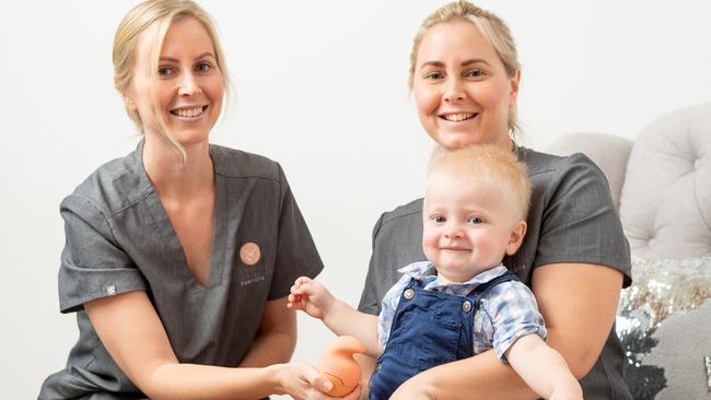 Darwin twin nurses Jessica Whalley Hair and Samantha Hair are pictured with their product the Baby Bum Shower and baby Rocko, 1. Photograph: Che Chorley