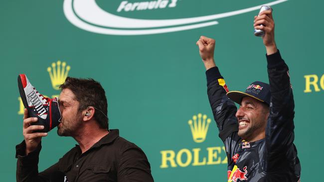 Actor Gerard Butler downs a shoey on the podium after the US Formula One GP with Red Bull Racing’s Daniel Ricciardo. Picture: AFP