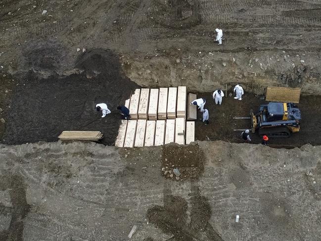 Workers wearing personal protective equipment bury bodies in a trench on Hart Island in the Bronx borough of New York.