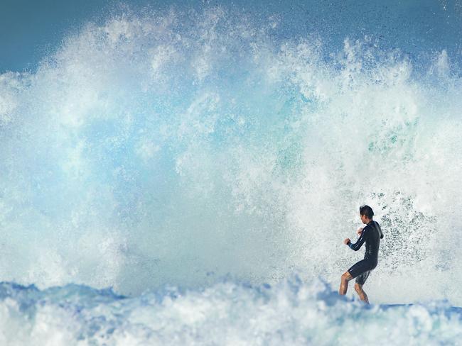 A surfer dwarfed by whitewater at Sunrise Beach as a southerly swell from an east coast low pushes big waves into south east. Queensland. Photo Lachie Millard