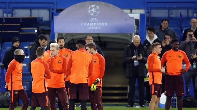 Barcelona players stand chatting on the pitch during a training session at Stamford Bridge