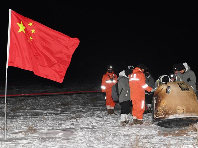 Researchers work around Chang'e-5 lunar return capsule carrying moon samples next to a Chinese national flag, after it landed in northern China's Inner Mongolia Autonomous Region, December 17, 2020. China Daily via REUTERS  ATTENTION EDITORS - THIS IMAGE WAS PROVIDED BY A THIRD PARTY. CHINA OUT.     TPX IMAGES OF THE DAY