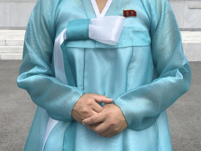A factory guide in a traditional Korean dress with the faces of the late North Korean leaders Kim Il Sung and Kim Jong Il pinned above her heart on the left of her dress. Picture: Wong Maye-E/AP