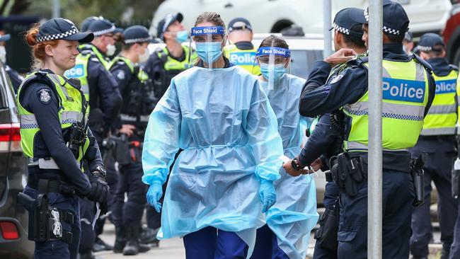 Medical staff are supported by police officers outside the public housing towers in Flemington. Picture: Getty