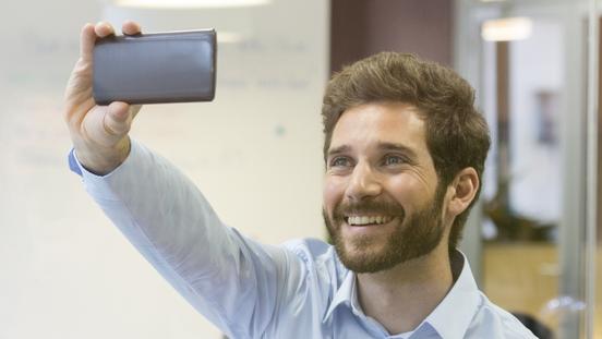 Handsome man doing selfie at office with mobile phone