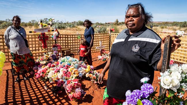 Leanne Oldfield, Walker’s foster mother, visits his gravesite in Yuendumu with relatives Meggerie Brown and Lara. Picture: Amos Aikman