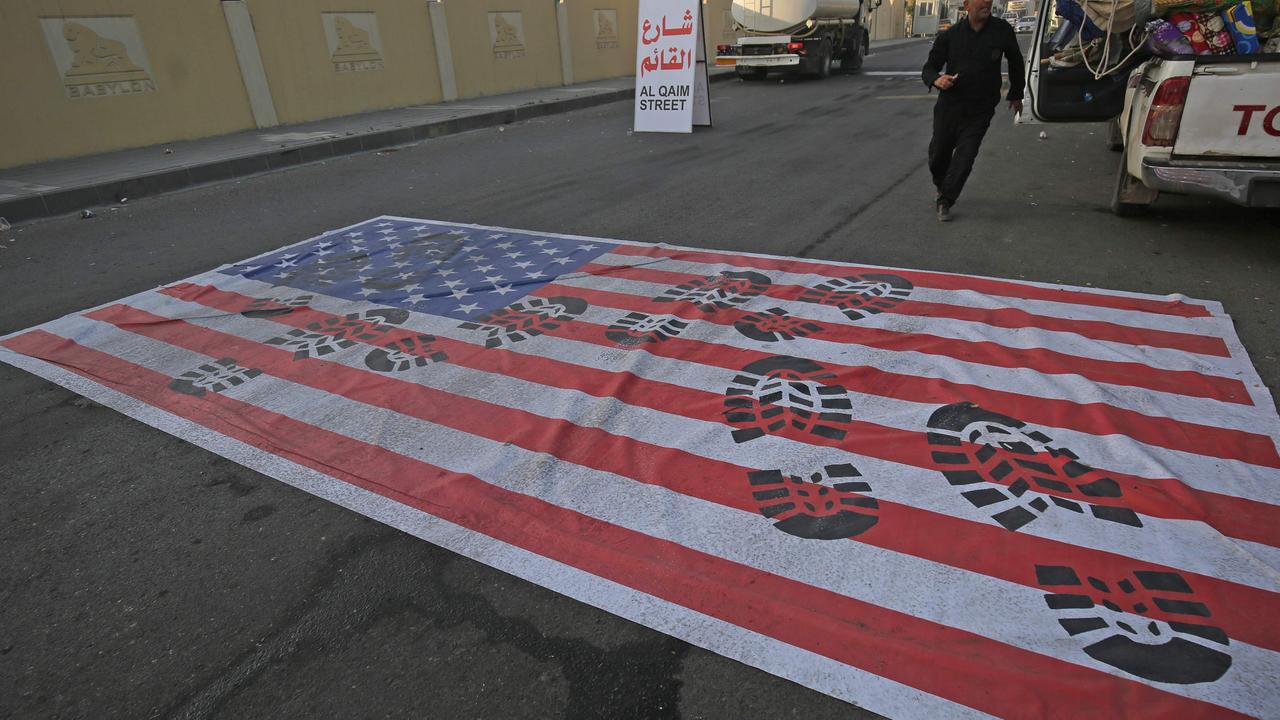 A mock US flag is laid on the ground for cars to drive on in the Iraqi capital of Baghdad on January 3 following the air strike. Picture: AHMAD AL-RUBAYE / AFP.