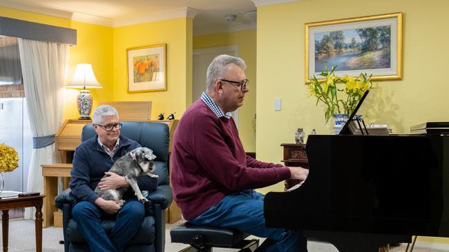 Peter Sanders playing piano at his home in Armidale, with his husband Peter Grace watching on. Picture: Simon Scott