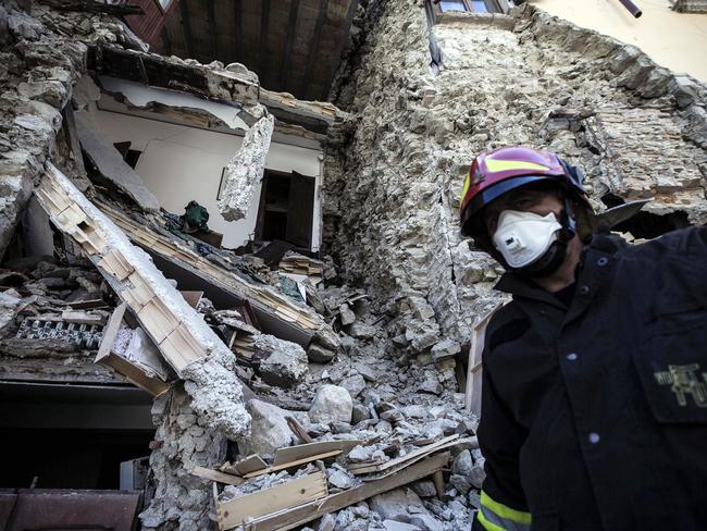 A firefighter walks past a collapsed house in Arquata, central Italy, Thursday, Aug. 25, 2016 where a 6.1 earthquake struck just after 3:30 a.m., Wednesday. Rescue crews raced against time Thursday looking for survivors from the earthquake that leveled three towns in central Italy, but the death toll rose to 241 and Italy once again anguished over how to secure its towns and cities, new and old, built on seismic lands. (Angelo Carconi/ANSA via AP)