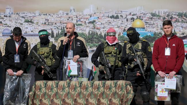 Israeli-American Sagui Dekel-Chen, left, Israeli-Argentinian hostage Yair Horn, third from left, and Israeli-Russian Sasha Trupanov, right, stand on a stage next to Palestinian fighters during their handover over to a Red Cross team in Khan Younis in the southern Gaza Strip on Saturday. Picture: Eyad Baba / AFP