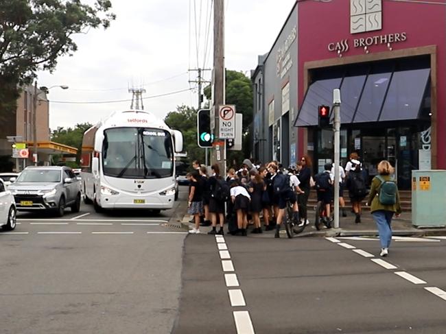 Children wait to cross the bustling Charing Cross intersection to get to school