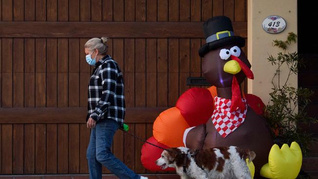 A pedestrian wearing a face mask walks their dog past an inflatable turkey in California ahead of the Thanksgiving holiday. Picture: AFP