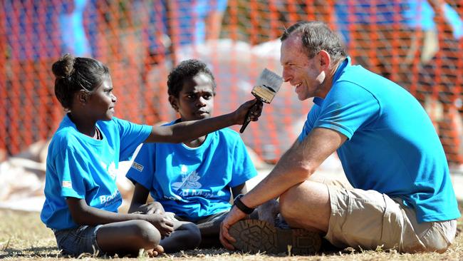 An 11-year-old Waynead Wolmby (centre) helps to paint former prime minister Tony Abbott’s nose during Mr Abbott’s 2012 visit to Aurukun’s school. Picture: File photo