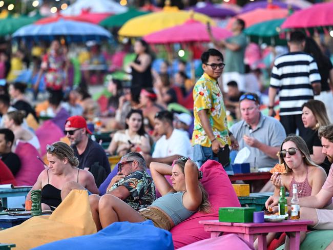 Foreign tourists relax on the Kuta Beach near Denpasar on Indonesia's resort island of Bali on November 18, 2023. (Photo by SONNY TUMBELAKA / AFP)