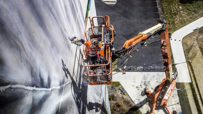 World-renowned large/scale artist Guido van Helten painting a 10-storey building at Southern Cross University Gold Coast campus. Picture: NIGEL HALLETT