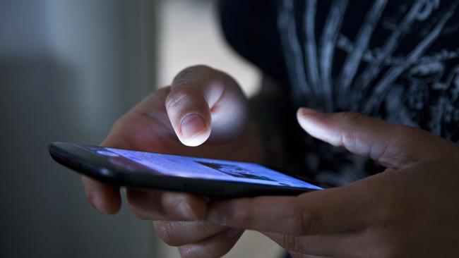 Hands holding smartphone in the dark.