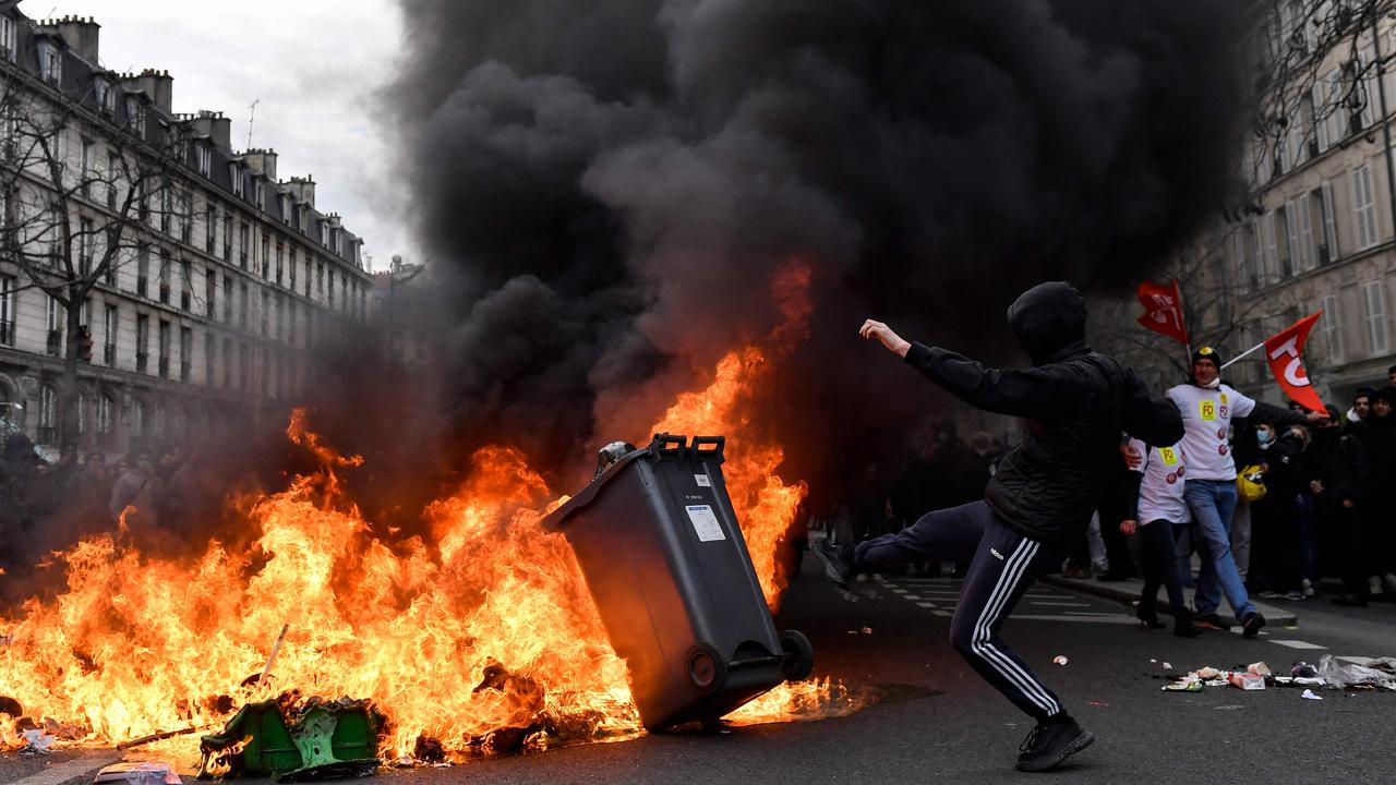 A protester kicks a bin into a fire during strikes and protests in Paris last year. Picture: Julien De Rosa / AFP