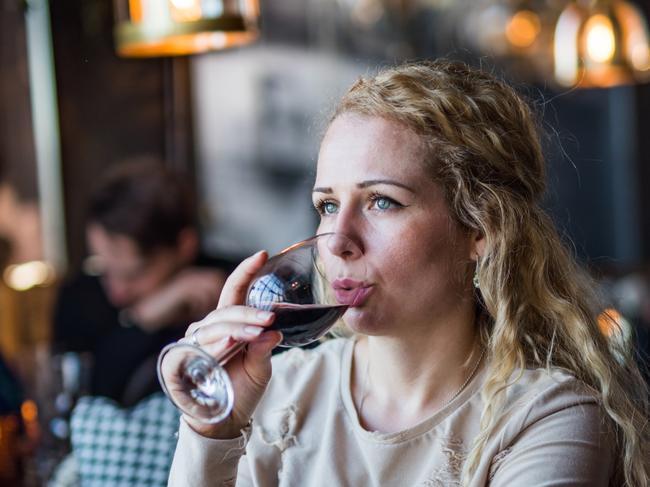 Young businesswoman having a break in restaurant and drinking red wine at sunset.