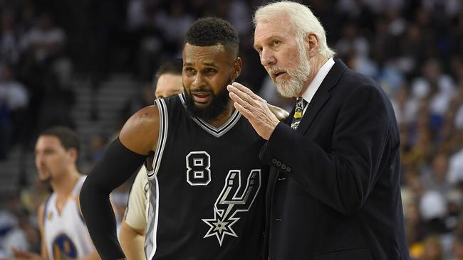 Head coach Gregg Popovich of the San Antonio Spurs talks with player Patty Mills.