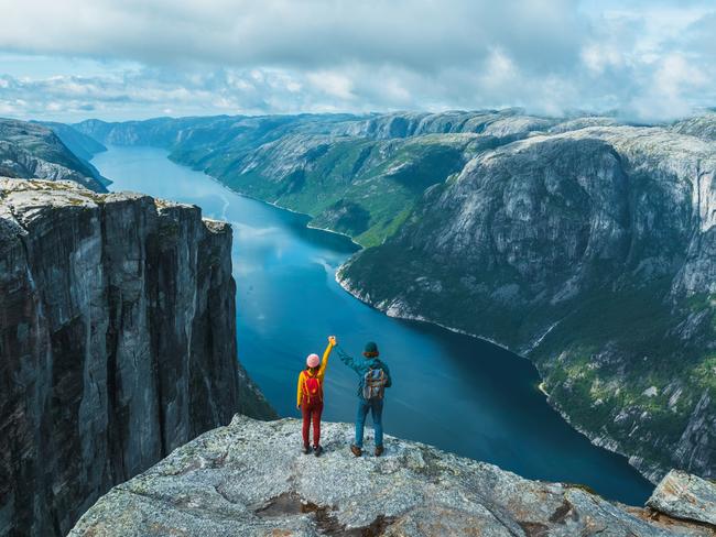 Scenic view of man and woman  raising holding arms  in mountains in Norway on the background of the fjordEscape 19 May 2024Doc HolidayPhoto - iStock