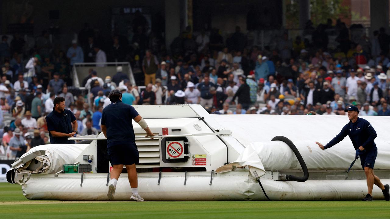 Groundstaff bring on the covers as rain delays play on day one. Picture: AFP